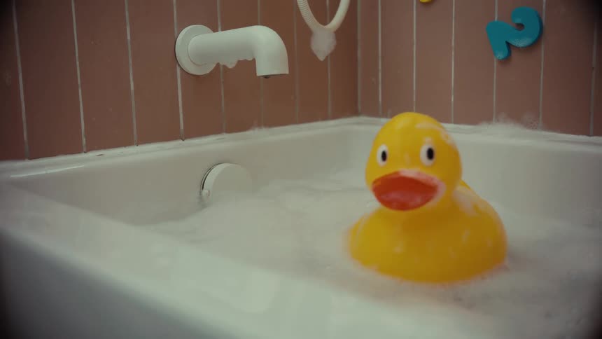 A lonely yellow rubber duck floats in a bathtub full of bubbles
