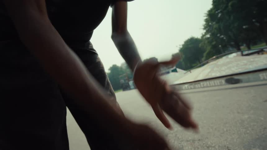 A close-up shot of a skateboarder dusting their hands before pushing off and riding away at the skatepark