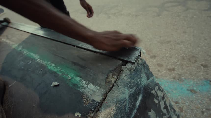 Close-up of a skateboarder applying wax to the metal coping of a skate ramp
