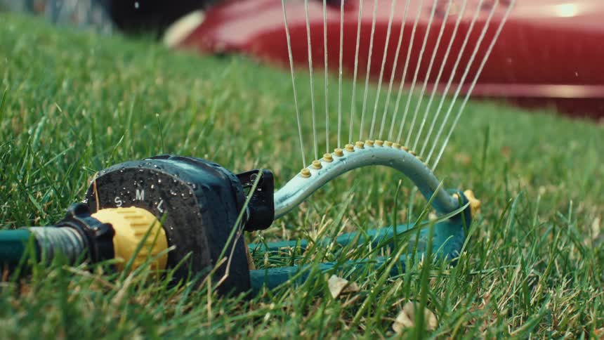 Close-up of a lawn sprinkler watering the grass in slow motion
