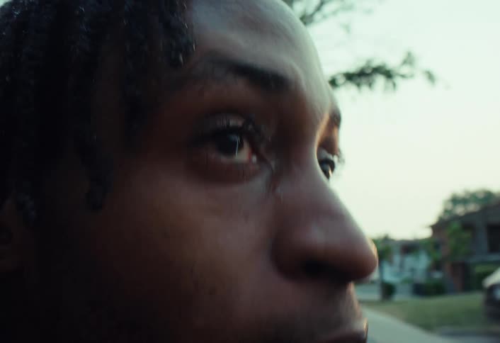 A slow-motion close-up of a sweaty African American man wiping his face with his sleeve, showing determination and focus