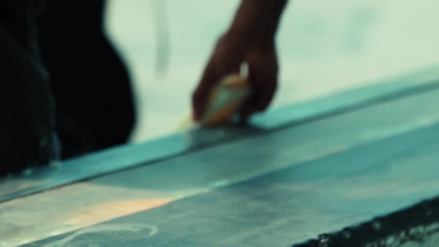 Slow motion close-up of a person waxing a grind rail at a skate park