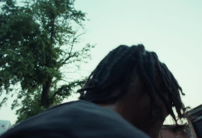 Low angle slow motion close-up of a focused young Black man with dreadlocks getting on his skateboard and riding away
