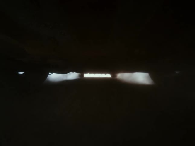 A low-angle POV from underneath a car shows the road rushing by at high speed as it drives through light and shadow