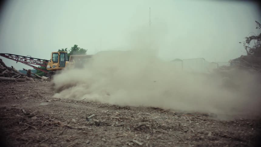 A race car drifts on a dirt road in a junkyard, kicking up a huge cloud of dust in slow motion