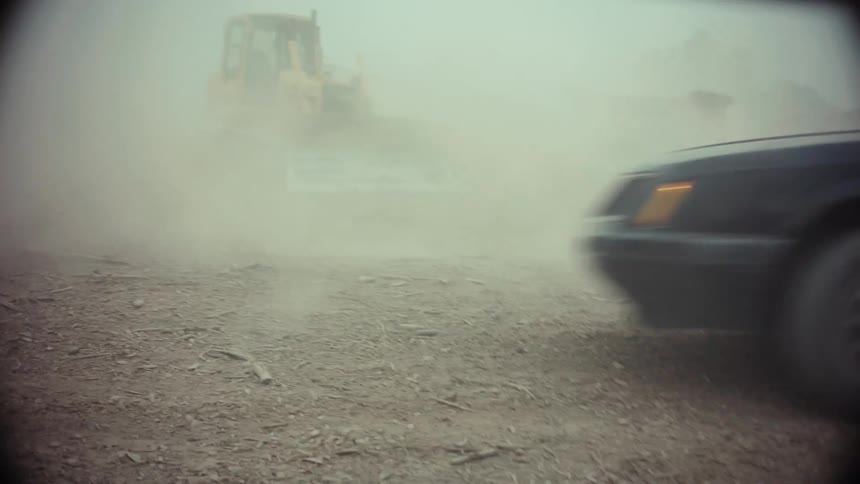 Drivers with paintball guns engage in a chaotic car chase through a dusty, post-apocalyptic landscape in this gritty, vintage-style clip