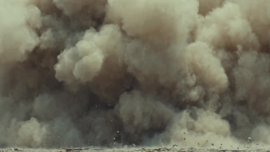 A massive cloud of dust and debris explodes outwards from a car doing a burnout in super slow motion