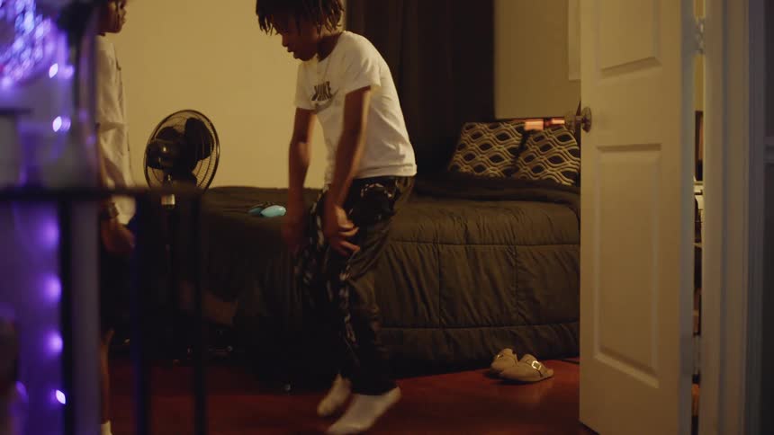 Two joyful young brothers laugh and dance together in slow motion in their dimly lit bedroom