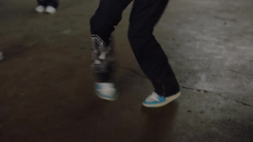 A dynamic male dancer passionately performs an intense hip-hop routine with his crew in a gritty industrial warehouse