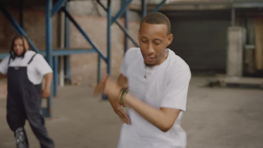 A skilled dancer performs an intense and energetic hip-hop routine inside a raw, industrial warehouse
