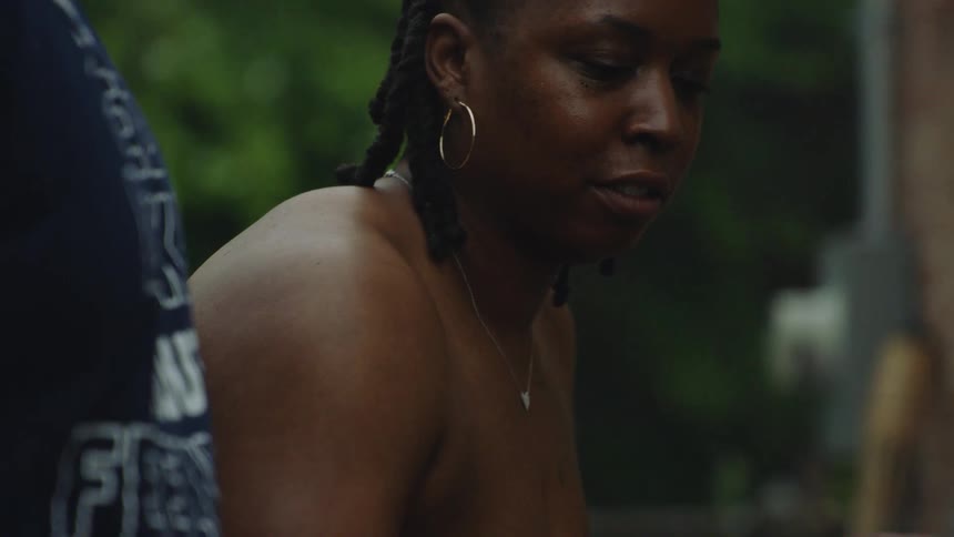 Close up in slow motion of an African American couple grilling sausages and burgers at a backyard barbecue