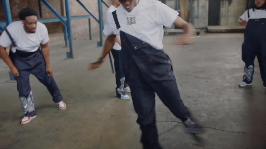 A talented dance crew in matching outfits performs an energetic and synchronized street dance routine in a vast industrial warehouse