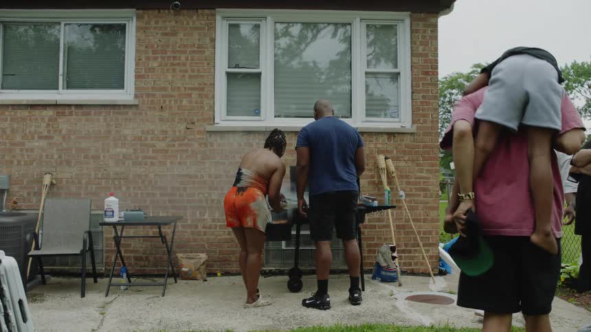 Friends and family gather for a lively backyard barbecue, with a man giving a child a piggyback ride in slow motion