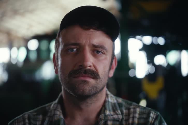 Portrait of a serious farmer looking up at the camera with a solemn face inside a barn