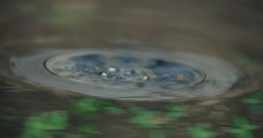 A close-up shot of a dirty car tire spinning quickly while driving on a dirt road