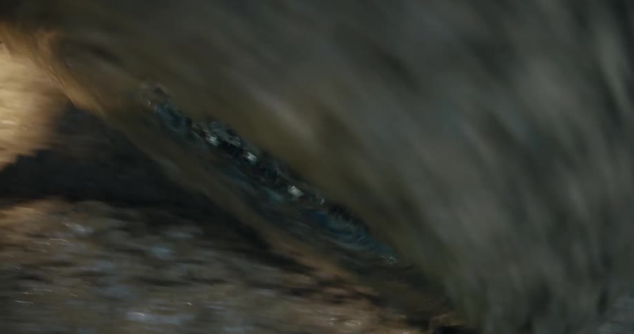 Rainwater creates a powerful whirlpool as it drains into a muddy storm grate, with the camera spinning around the vortex
