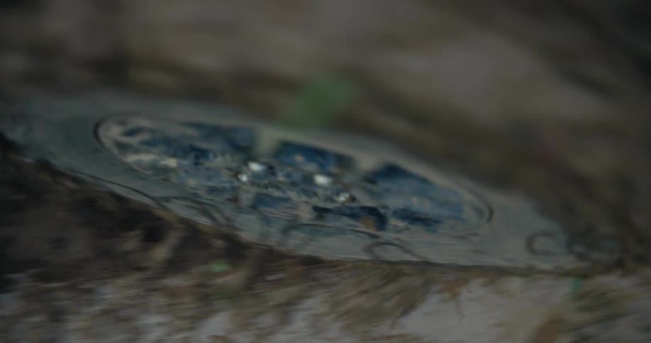 An erratic, blurry, and shaky handheld camera shot focuses on a solar-powered light embedded in a dirt path