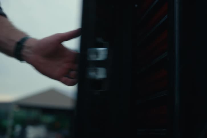 A man in slow motion opens a built-in toolbox on the side of a black truck and grabs a wrench to start his work