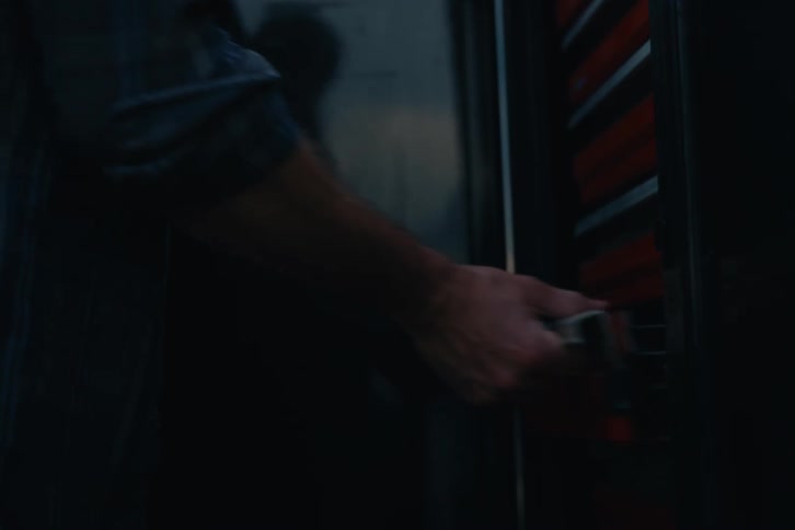 A man in slow motion closes his truck door and then gets a wrench from a built-in toolbox on the side of the vehicle