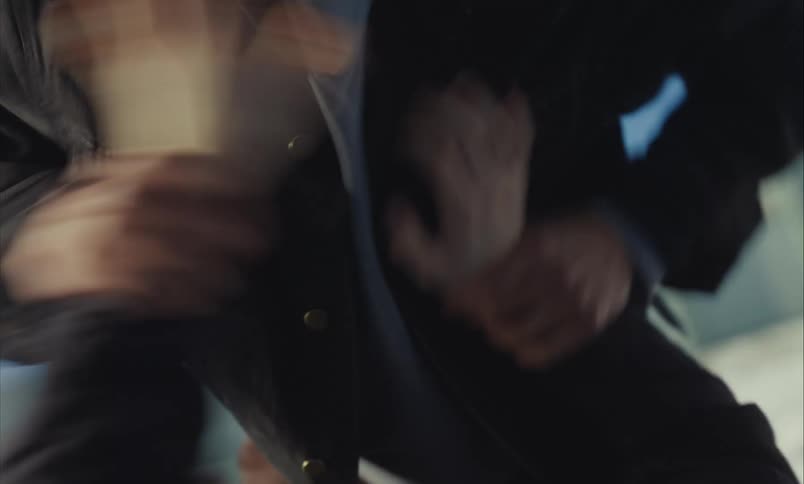 An intense, shaky close-up captures a violent struggle between two people outdoors