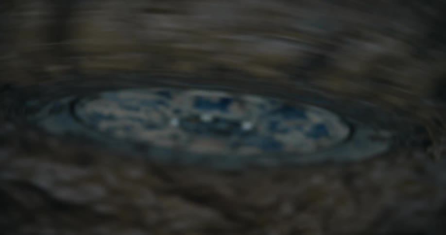 Out-of-focus close-up of murky water swirling and rippling around a drain
