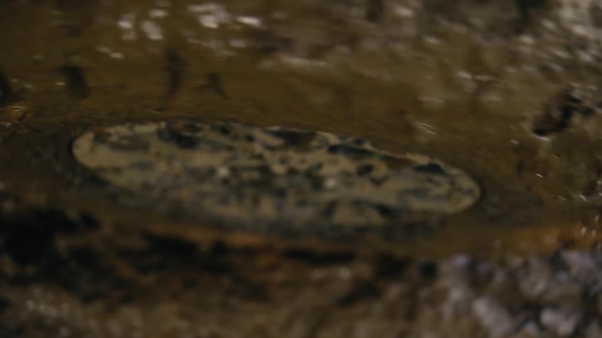 Slow motion close up of a muddy hi-hat cymbal vibrating and splashing water droplets with each hit
