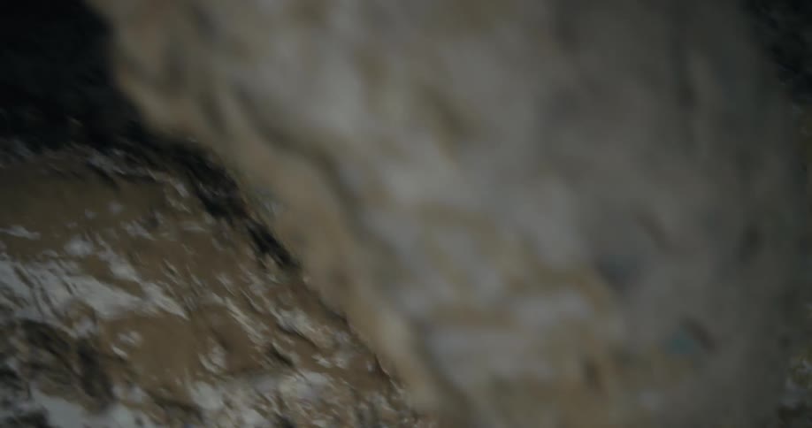Swirling muddy water engulfs a blue drain cover during a flood or heavy rainstorm