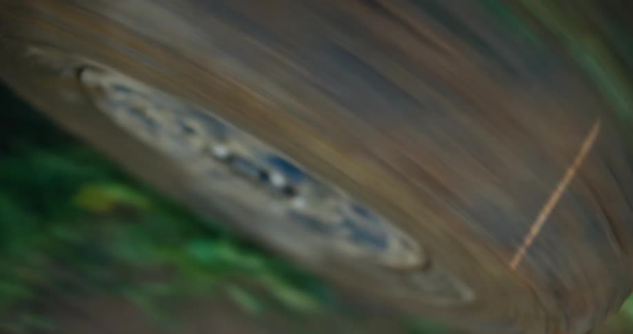 A soft-focus, close-up shot of a dirty off-road tire spinning at high speed