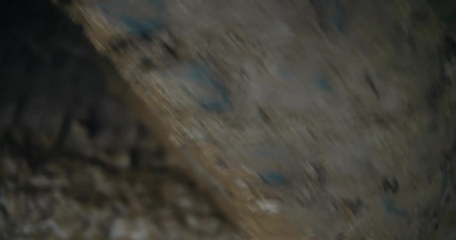 An out-of-focus, ground-level perspective captures the rapid spinning of a muddy tire on a vehicle driving off-road