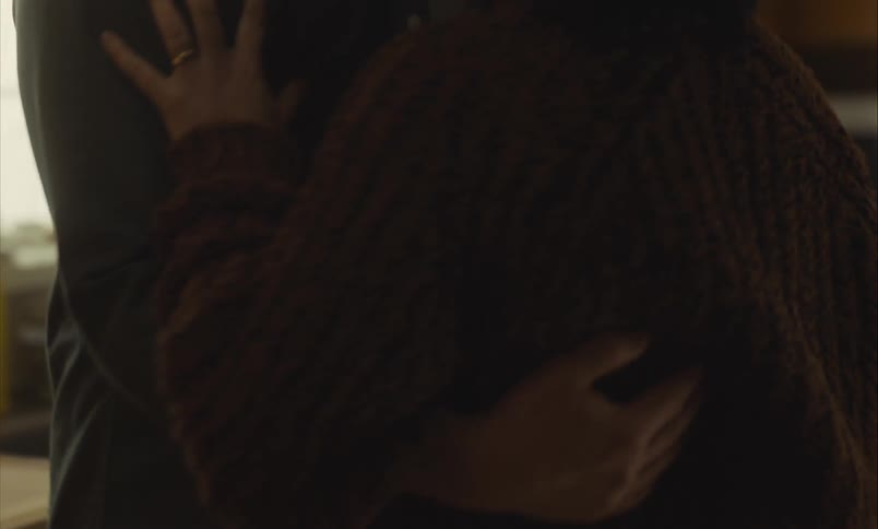 An intimate close-up shot shows a couple slow dancing and embracing in their dimly lit kitchen