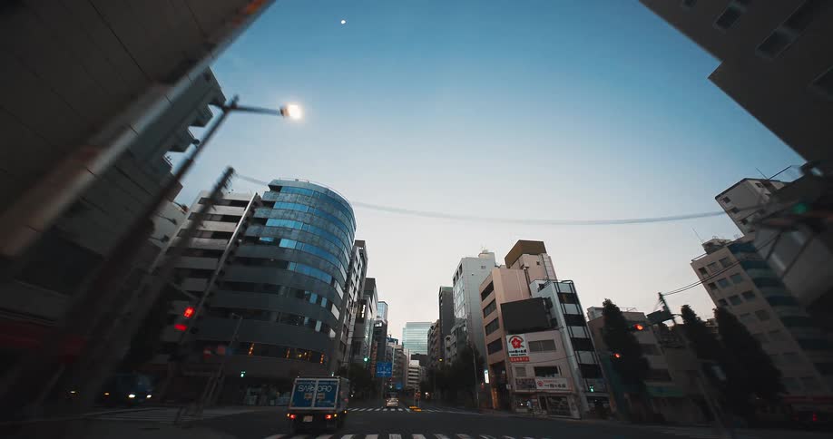 A point-of-view drive through the towering city streets of Tokyo under a clear early morning sky