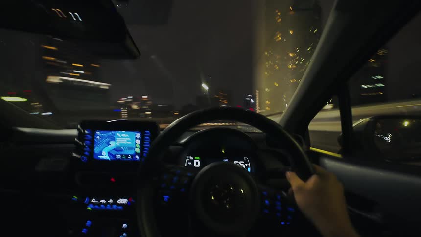 First-person view hyperlapse of a car speeding through a city highway at night, with blurred lights creating a sense of fast motion