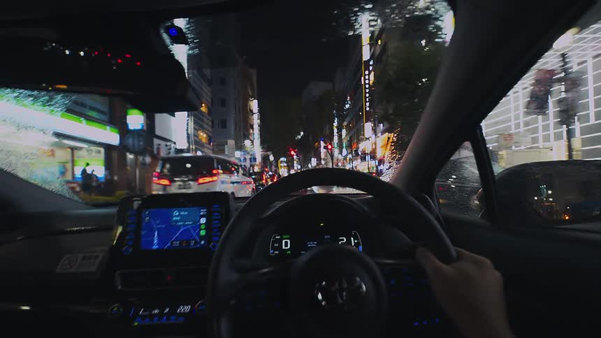 A first-person view of driving a modern car through the vibrant, rainy streets of Tokyo at night
