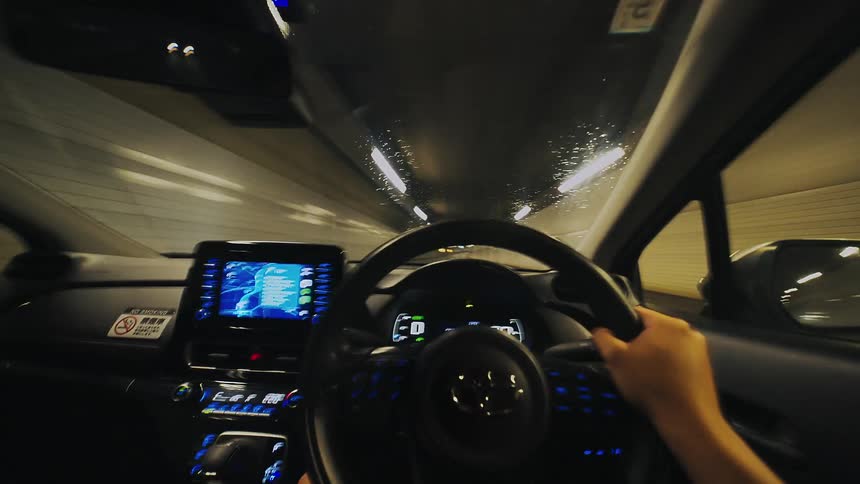 A fast-paced POV time-lapse shows a driver's hands on the steering wheel while speeding through a long, illuminated tunnel at night