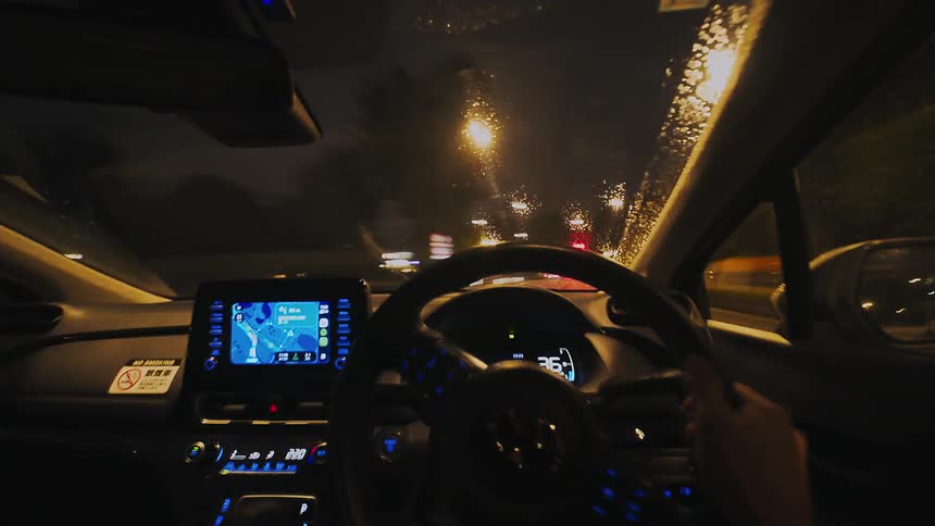 A dynamic first-person view time-lapse of driving through a city at night in the rain