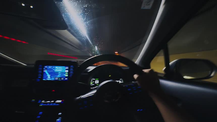 A first-person point-of-view time-lapse of driving a car through a rainy city at night, entering a tunnel as lights streak past