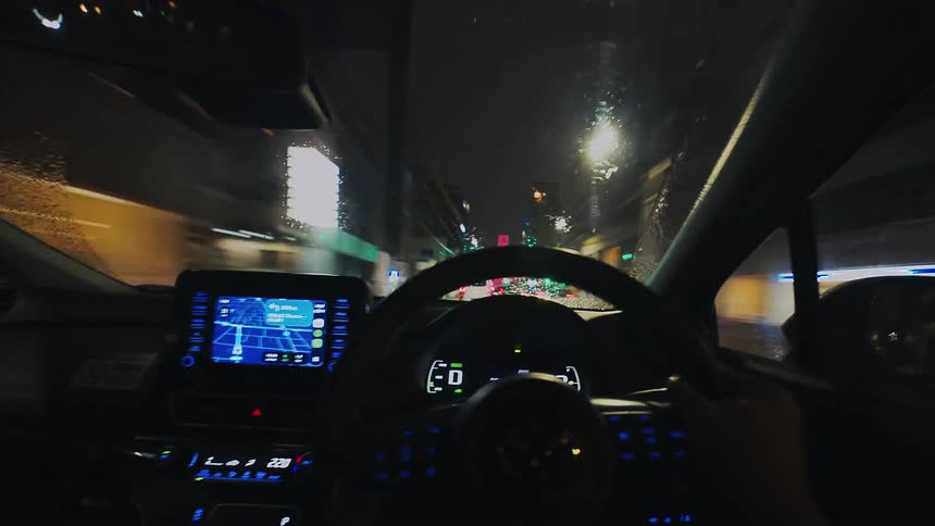 A point-of-view timelapse from inside a car driving through the glowing, rainy streets of a city at night