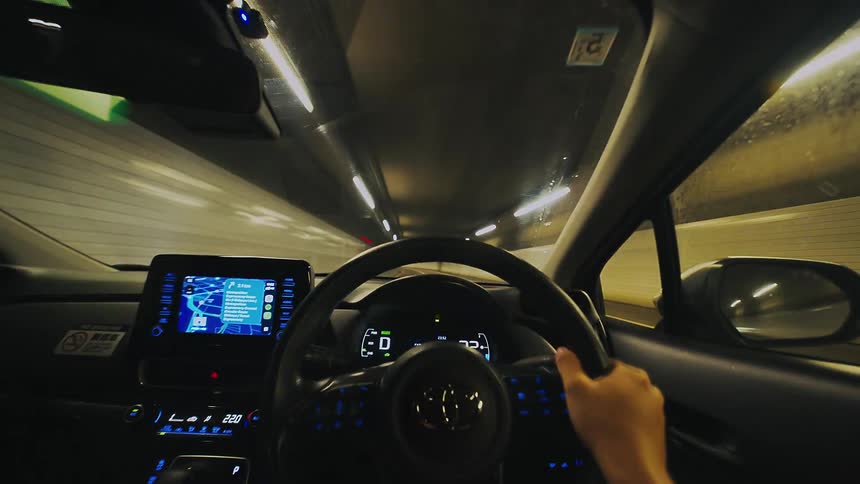 An immersive first-person point-of-view time-lapse of driving a modern car at high speed through a brightly lit tunnel at night
