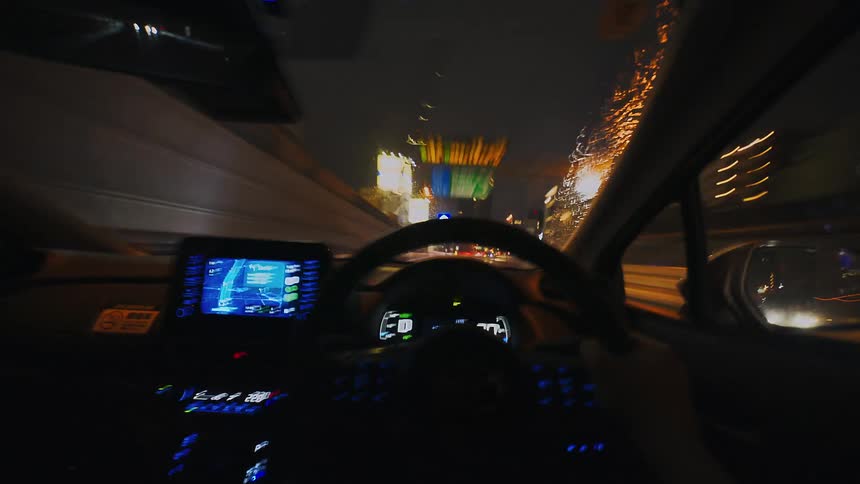 A fast-paced POV hyperlapse of driving through a city on a rainy night, with blurred lights streaking past the wet windshield