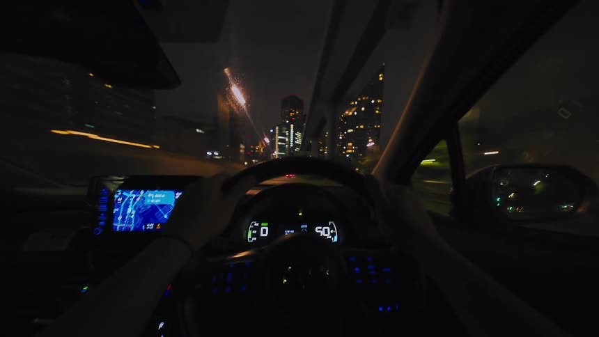Dynamic first-person point-of-view hyperlapse of a car speeding through the brightly lit streets of a modern city at night