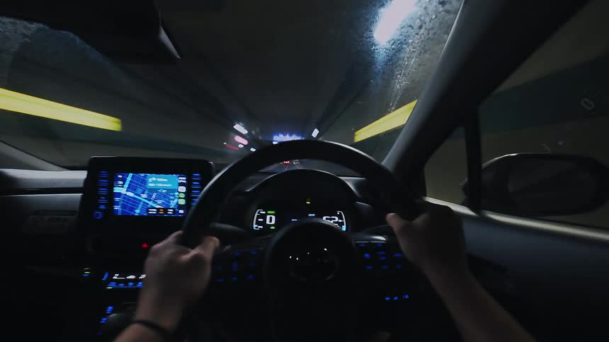 A first-person point-of-view hyperlapse of driving through a tunnel and emerging into a bustling, neon-lit city at night