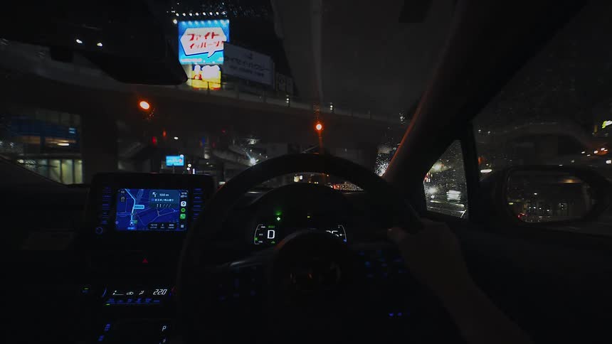 Driver's point of view of a rainy night drive through the illuminated city streets of Tokyo, Japan