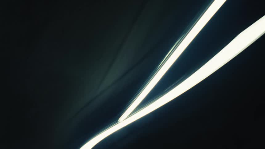 An abstract time-lapse of white and colored light trails speeding through the dark