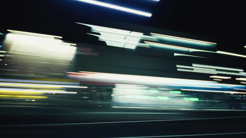 A dynamic time-lapse captures the vibrant city lights blurring into colorful abstract streaks while driving at night
