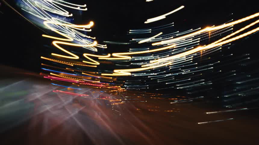 Abstract and dizzying long exposure time-lapse from a car driving at high speed through a city at night, capturing colorful streaks of light