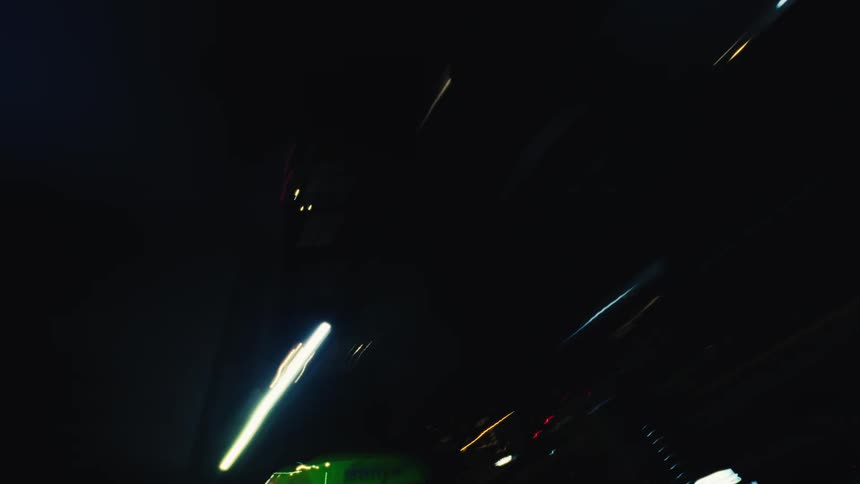 Driving through a dark city tunnel at night creates abstract colorful light streaks in this POV time-lapse