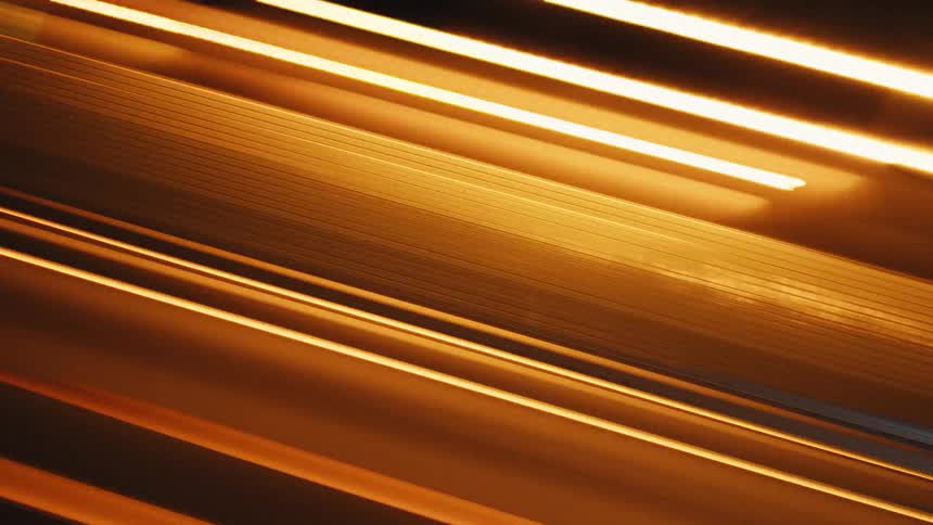 An abstract, diagonal view shows a long exposure time-lapse of city traffic light trails at night