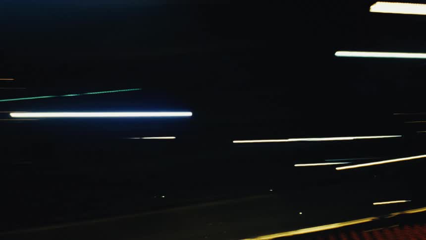 Dynamic, abstract streaks of colorful city lights blur past in a high-speed, long-exposure nighttime view