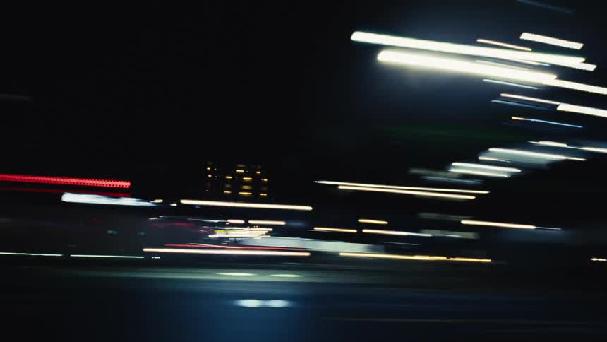 Driving through a vibrant city at night creates an abstract blur of colorful light streaks