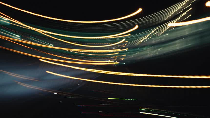 A mesmerizing point-of-view time-lapse of driving through a city at night, with abstract colorful light streaks blurring past